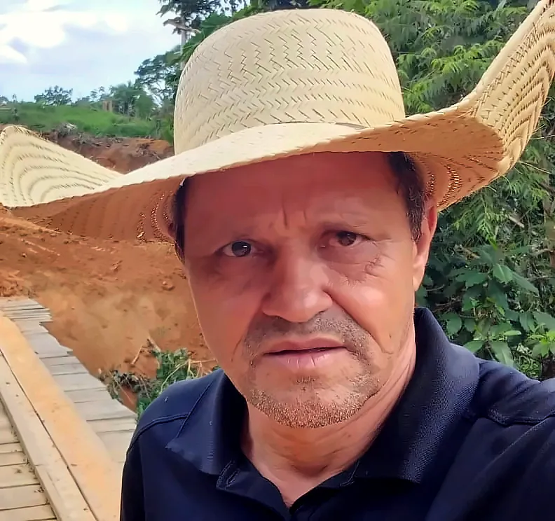 Abneir França de chapéu de palha, numa ponte de madeira